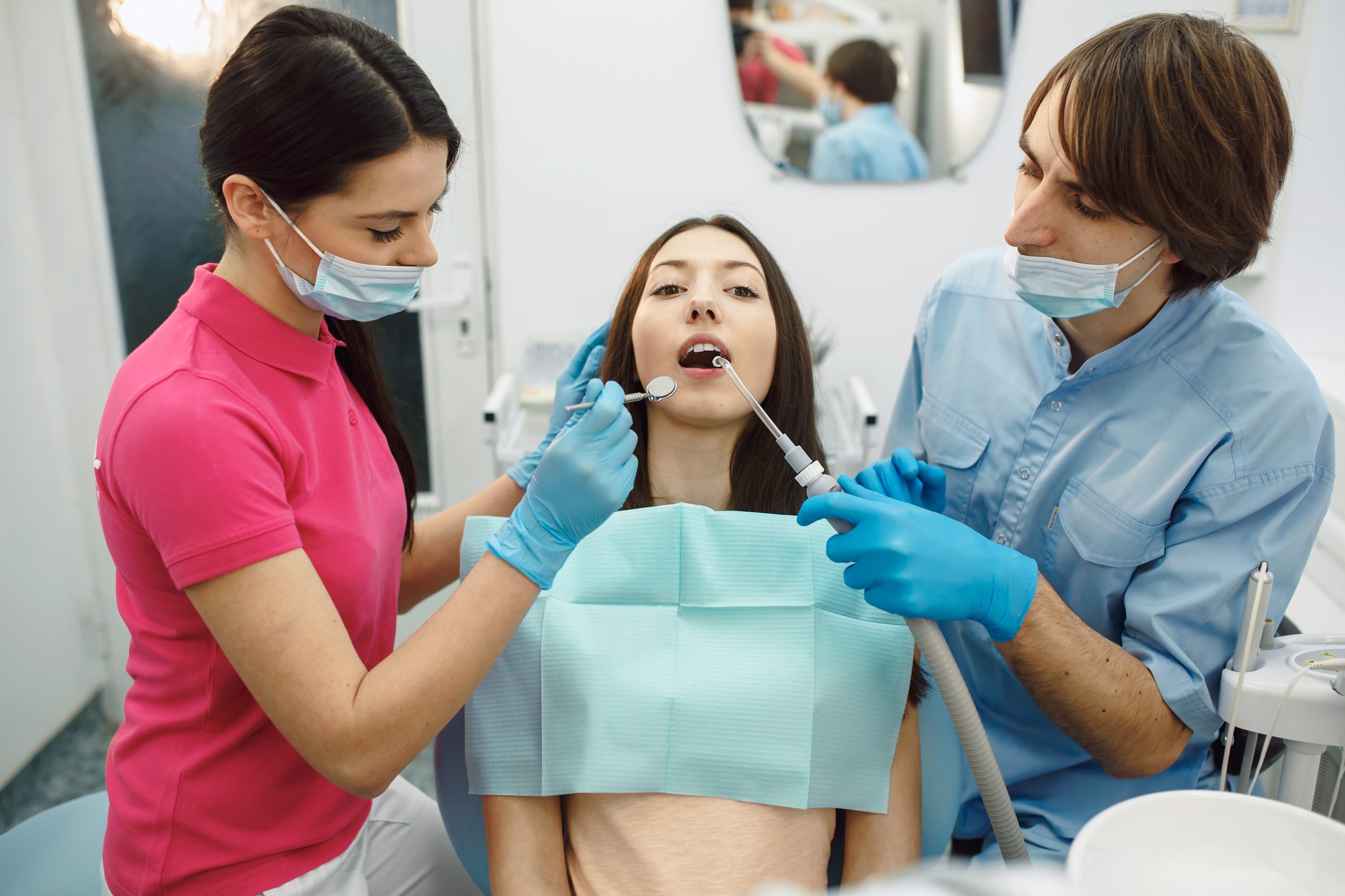 Inspection of the teeth of the girl with the help of a mirror.